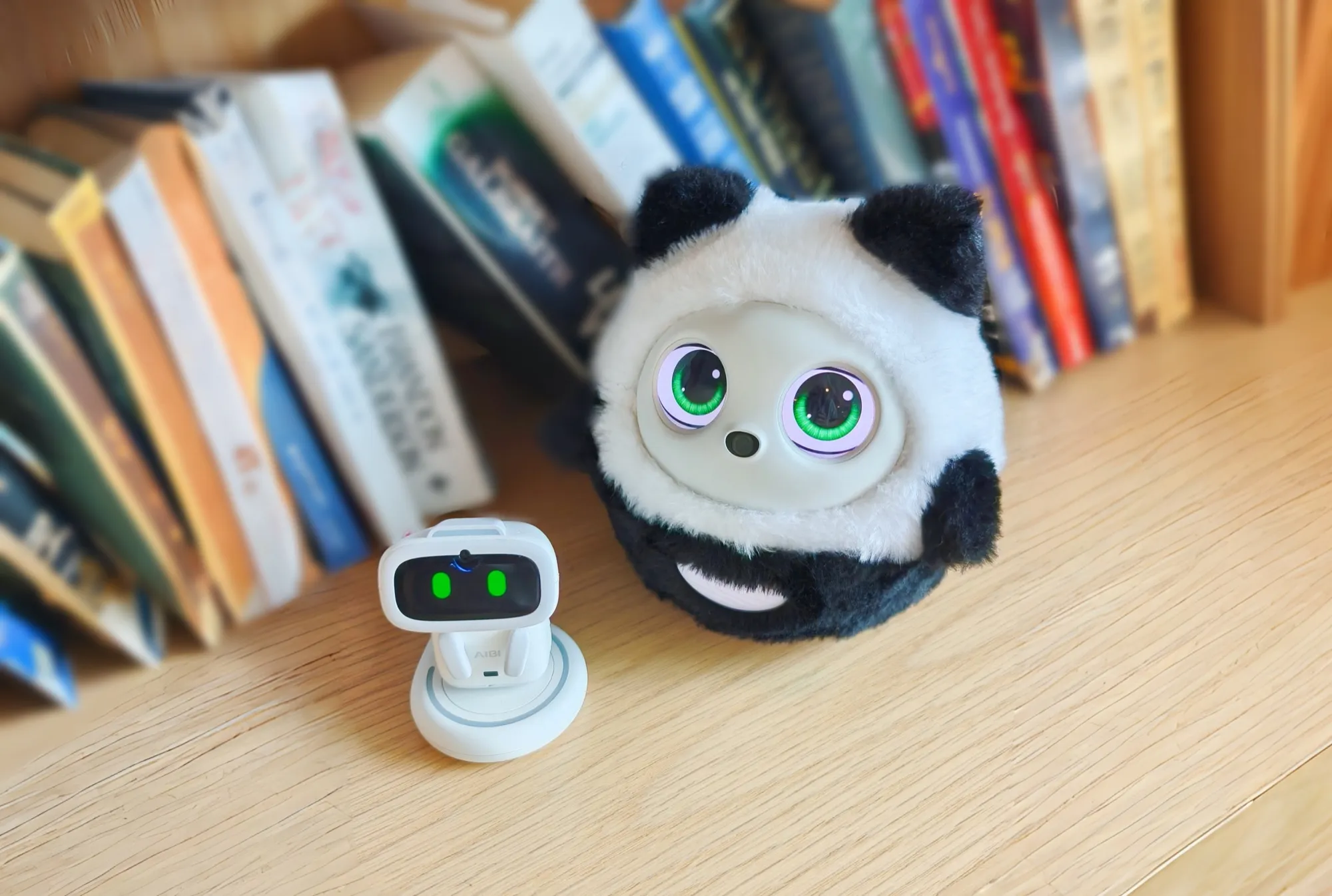 Pophie, the AI lifeform, side by side with AIBI, a pocket-sized AI pet on its charging dock